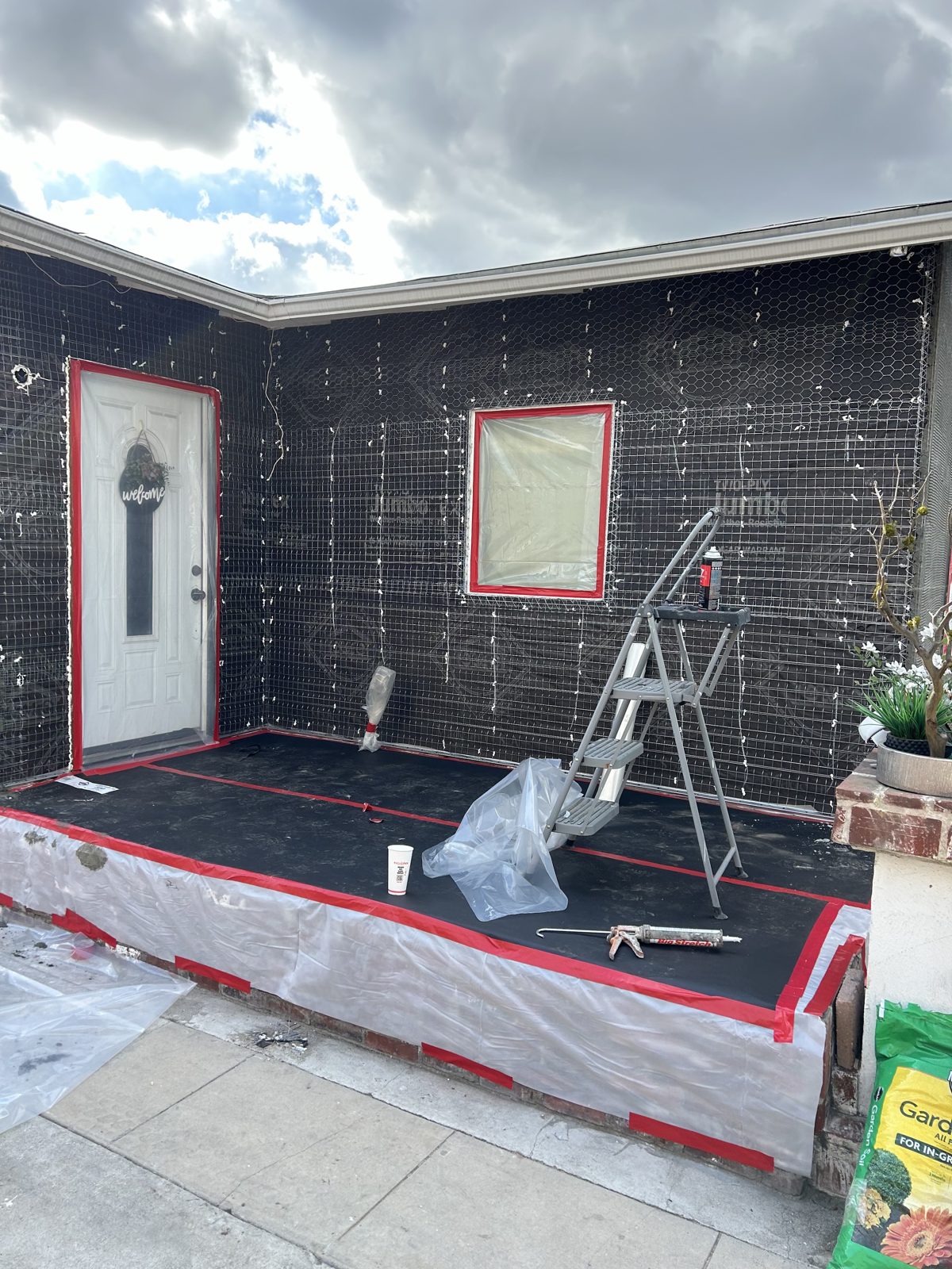 Wall wrapped in paper and wire mesh with door and window taped off