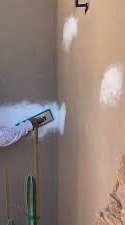 Fresh white patches on a tan stucco wall, smoothed with a float